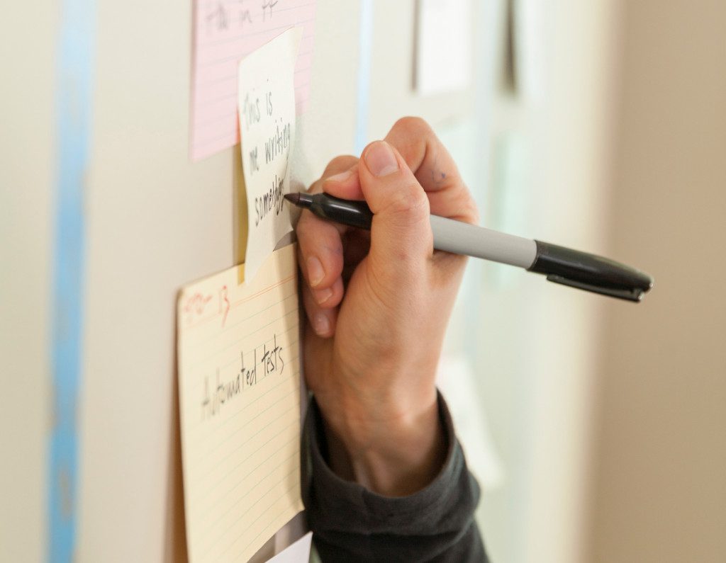 Agile software team member writing on the iteration card wall